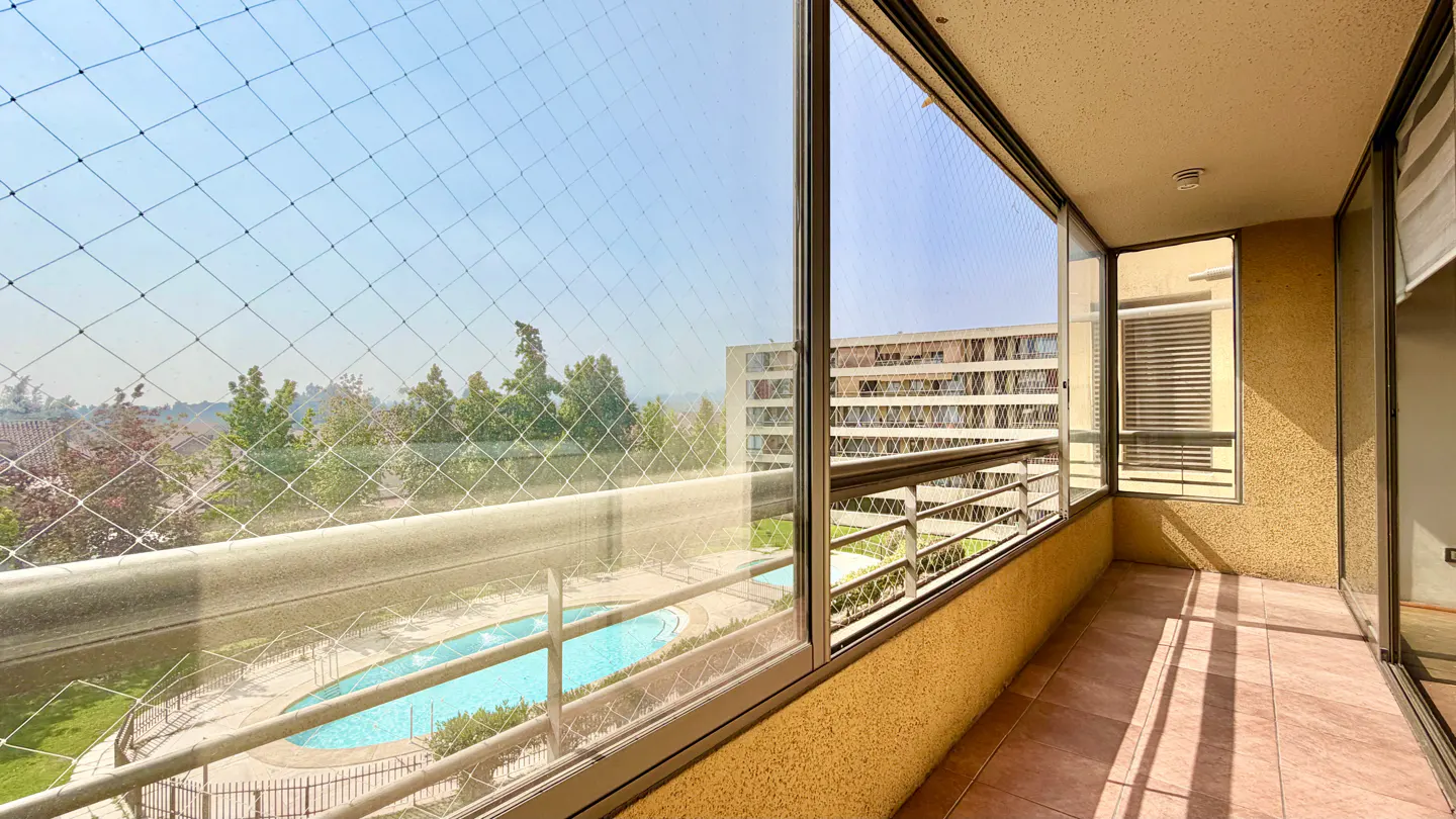 Balcony view with safety net overlooking a pool, trees, and building on a sunny day.