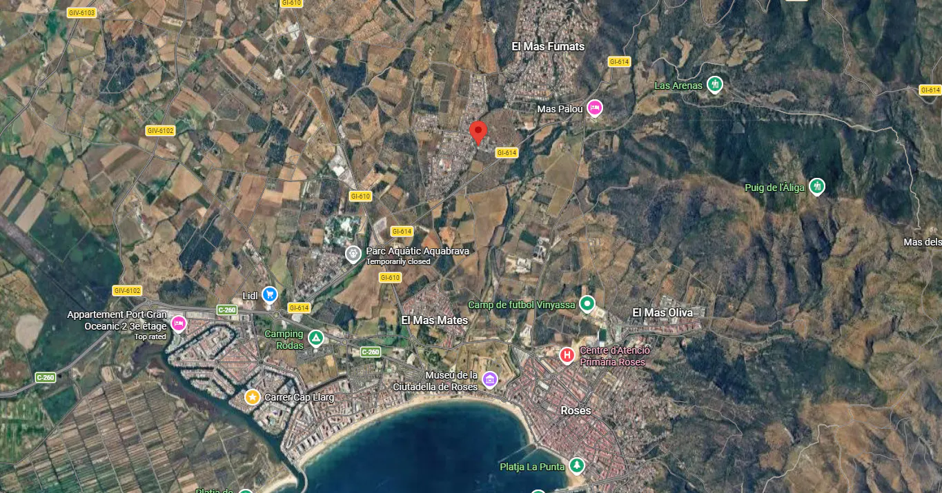 Aerial view of Roses, Spain, showing the coastline, city, and surrounding rural areas with a red pin marker.