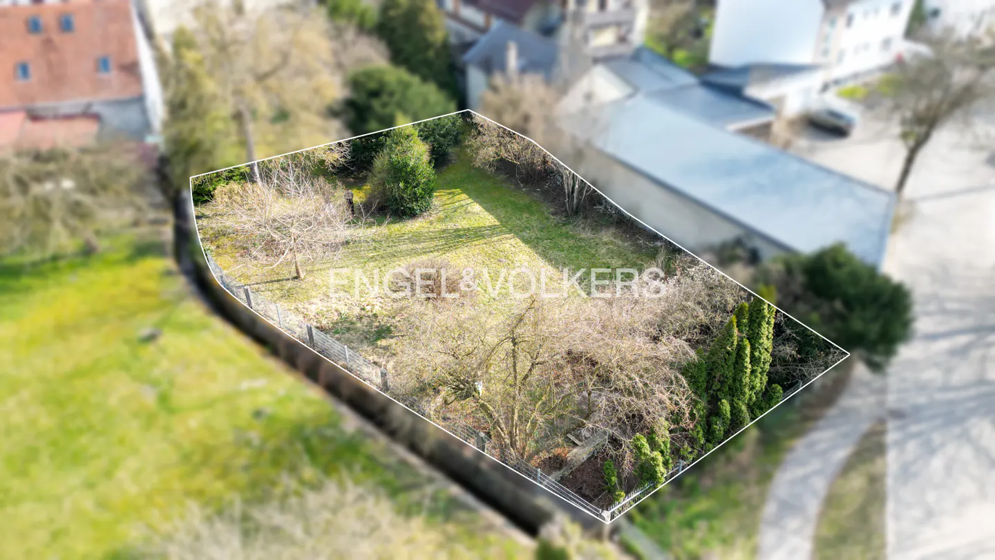 Aerial view of a vacant lot with a white border, trees, and grass. "Engel & Volkers" is superimposed on the image.