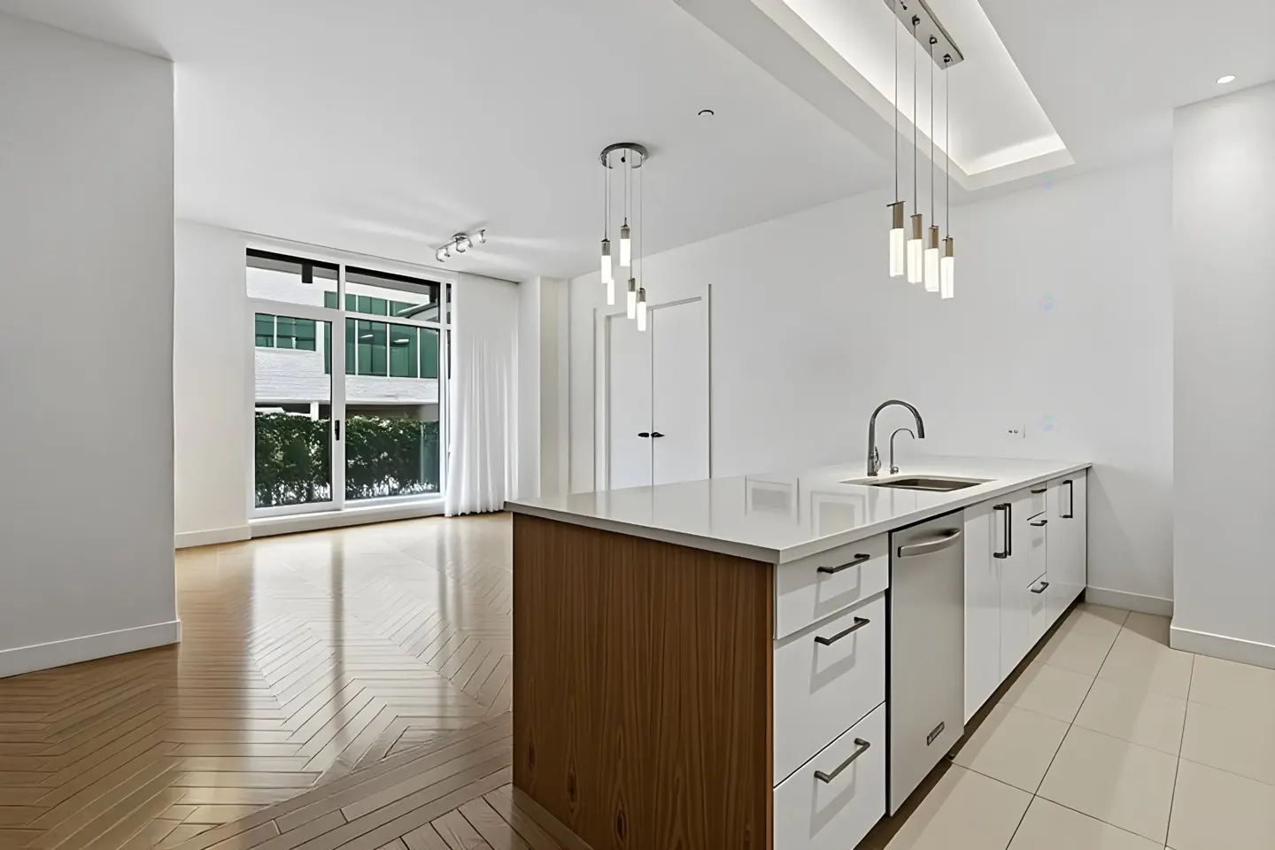 Bright, modern kitchen with white cabinets, wood island, and stainless steel appliances. Large window with natural light and herringbone wood floors.
