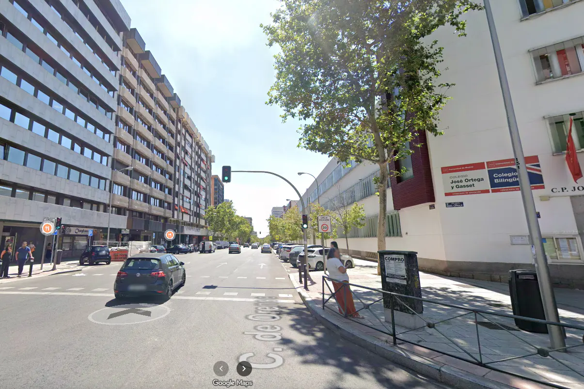 Street view of Calle de Orellana in Madrid, Spain, with cars, buildings, and a bilingual school.