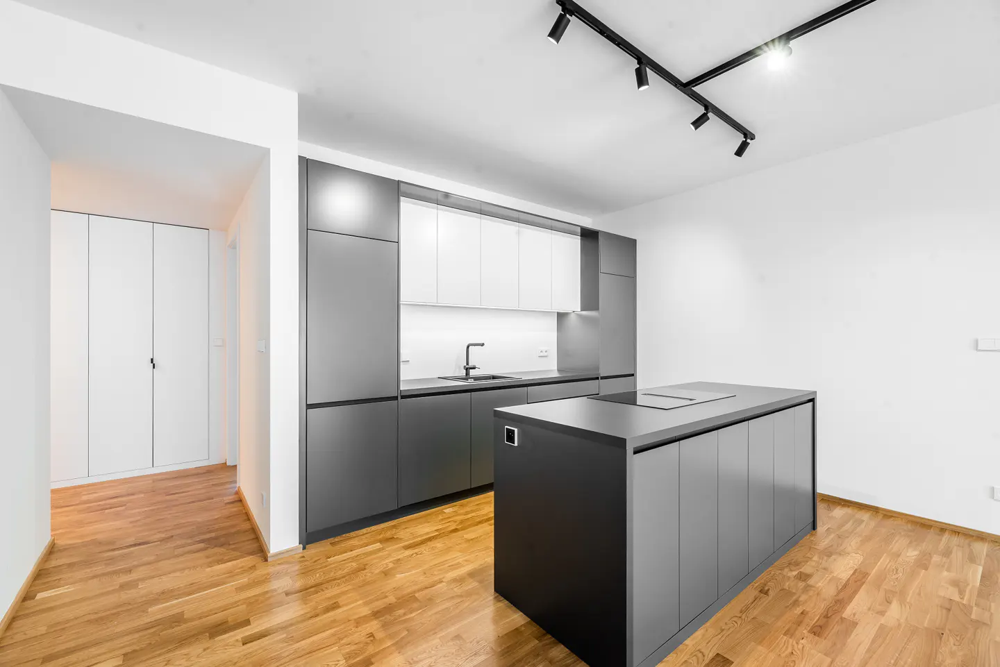 A modern kitchen with gray cabinets, white upper cabinets, and a gray island on a wood floor.