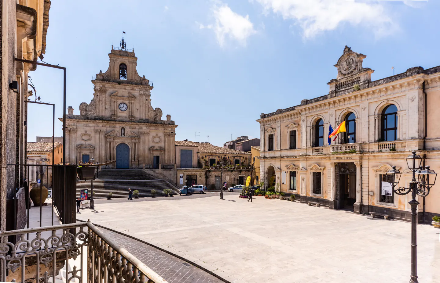 View of a town square with a church and municipal building under a blue sky.
