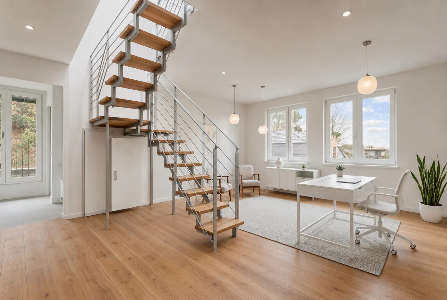 Bright, modern office space with wood floors, white walls, and a staircase with wood steps and metal railings. A white desk and chair sit near windows.