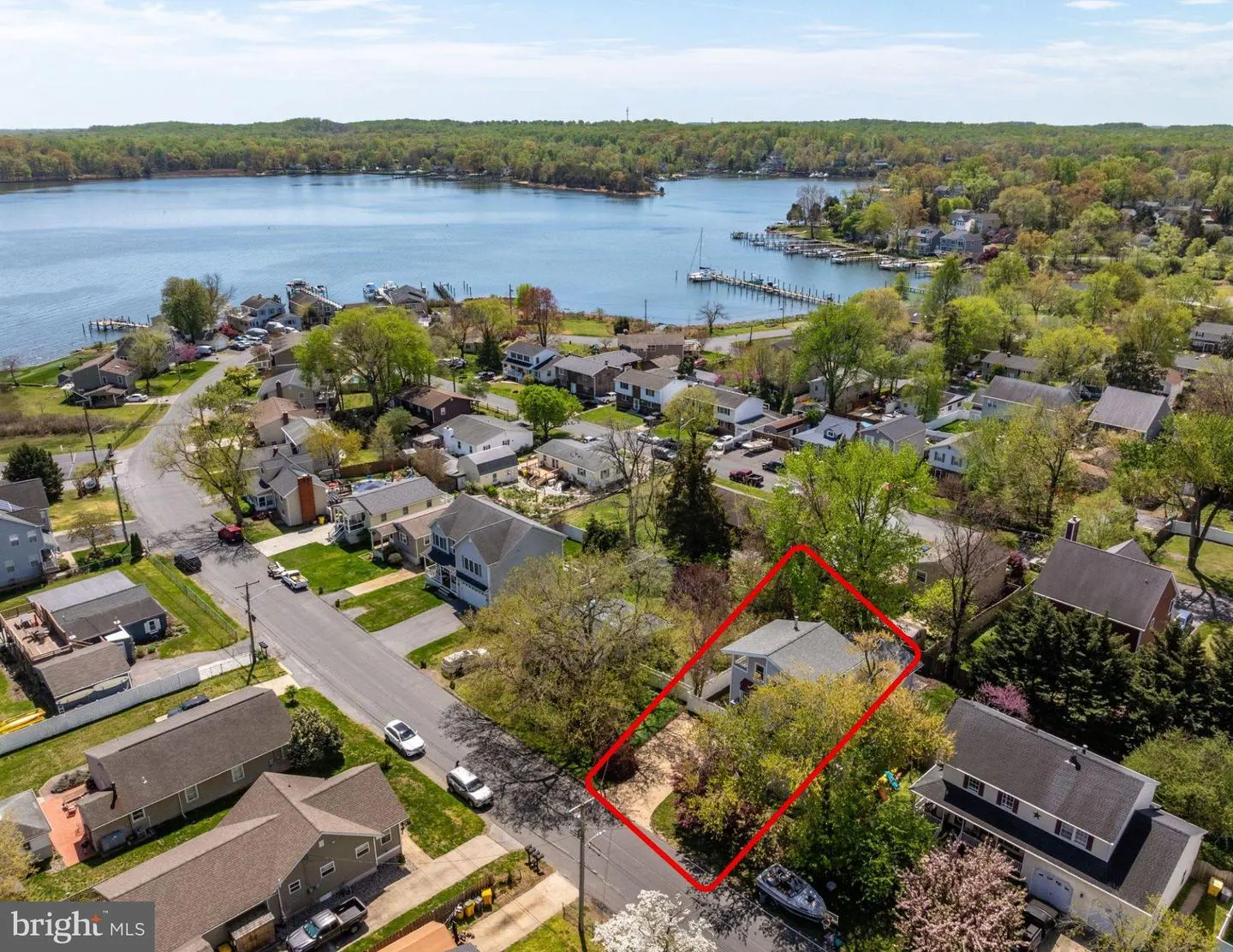 Aerial view of a neighborhood with a waterfront, showcasing a house outlined in red.
