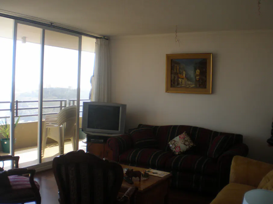 Living room with a striped sofa, painting, TV, and sliding glass doors to a balcony with a view.