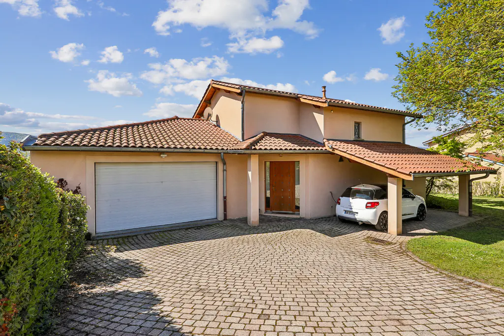 A tan two-story house with a red tile roof, a white garage door, and a white car parked under a carport.