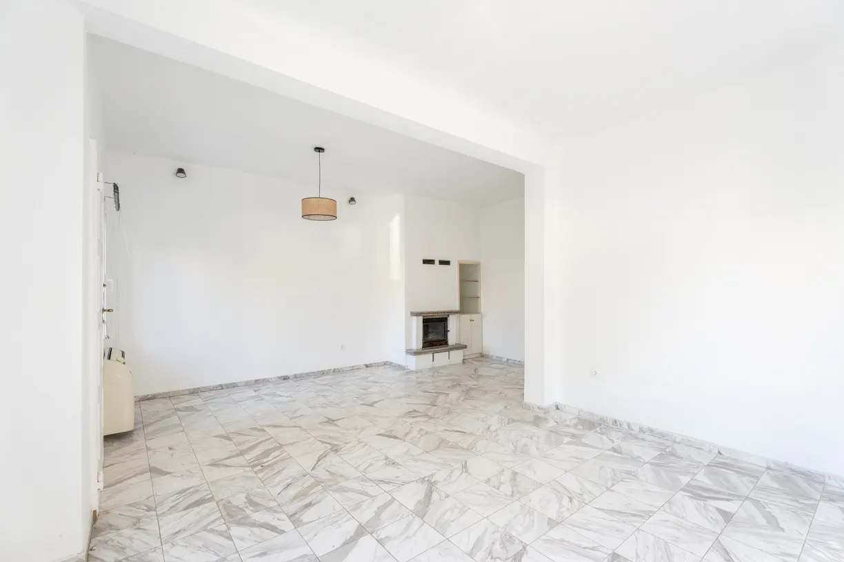 Bright, empty living room with white walls, marble-patterned tile floors, a pendant light, and a built-in fireplace.