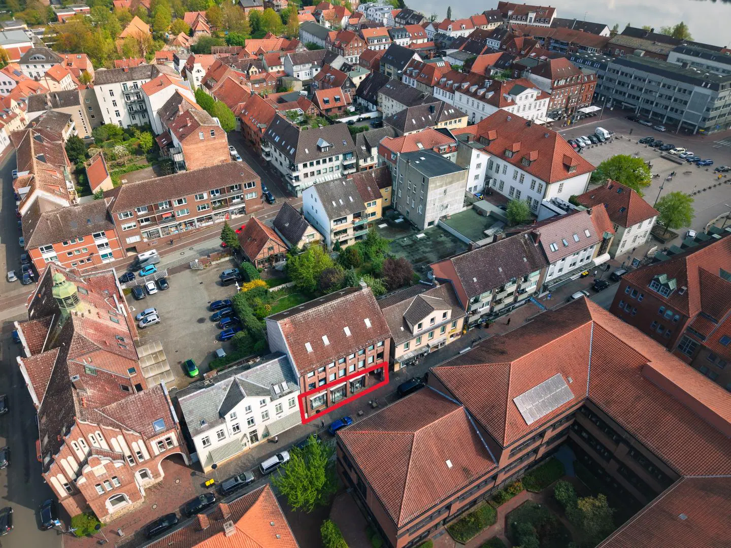 Aerial view of a European town with red-tiled roofs. A building is highlighted with a red border.