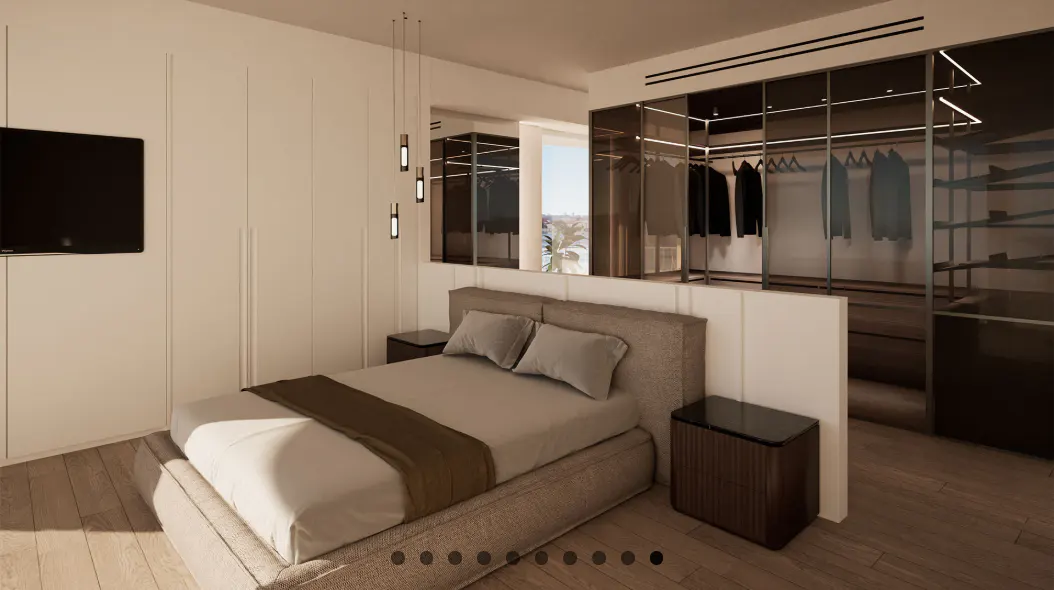 Bedroom with a gray bed, brown throw, and gray pillows. A black TV hangs on the white wall. A walk-in closet is in the background.