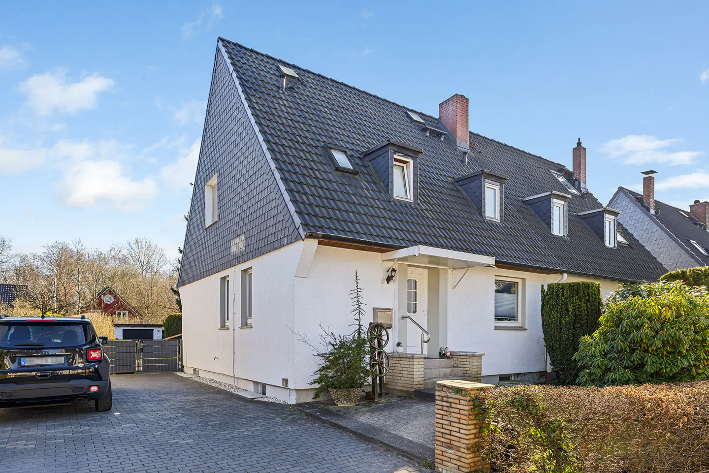 Exterior view of a white two-story house with a dark gray tiled roof and a black SUV parked in the driveway.