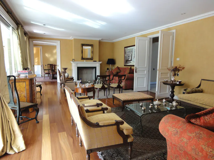 Spacious living room with yellow walls, hardwood floors, and classic furniture. A fireplace and open doorway add depth.