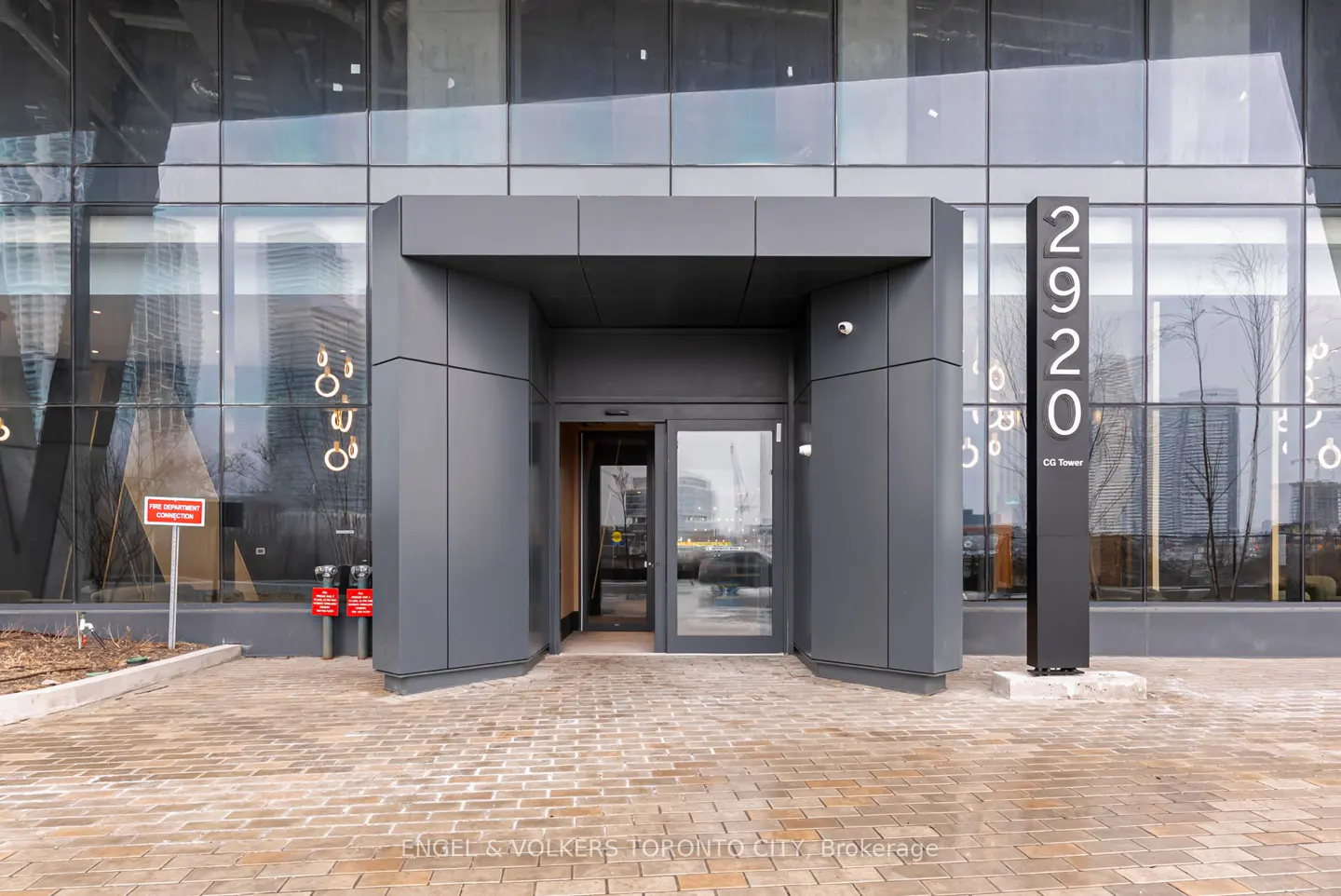 Exterior shot of 2920 CG Tower with gray entrance and glass doors on a brick walkway.