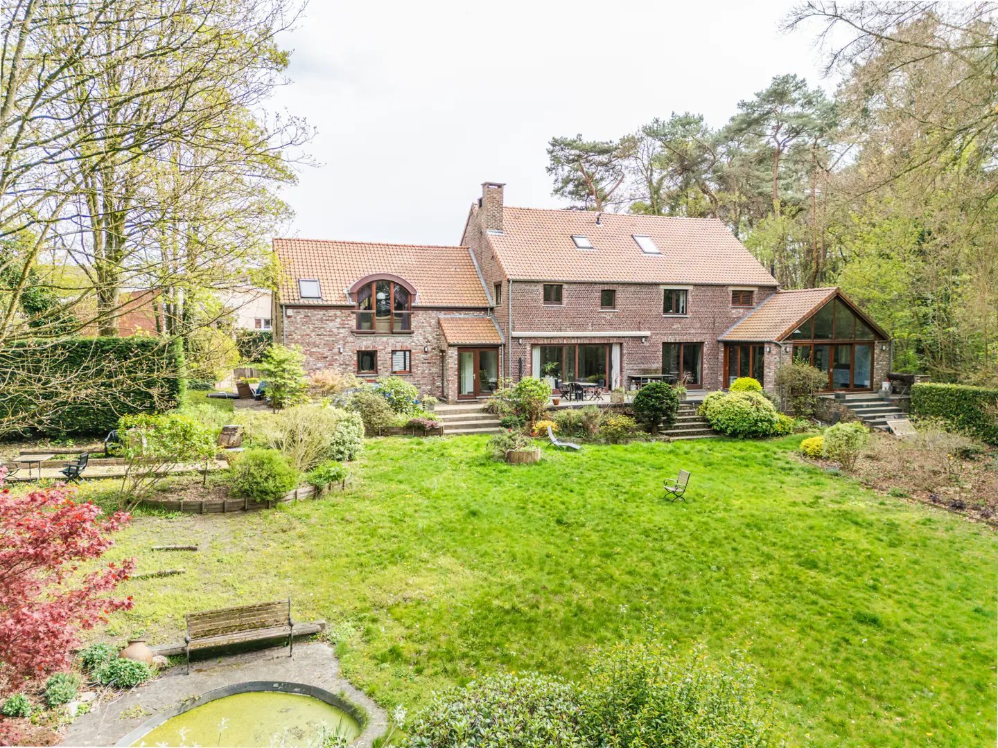 Exterior view of a large brick and stone house with a red tile roof and a green lawn.
