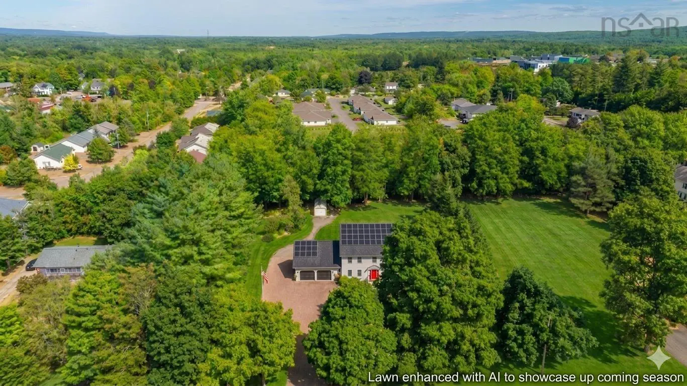 Aerial view of a two-story house with solar panels, a red door, and a large green lawn surrounded by trees.