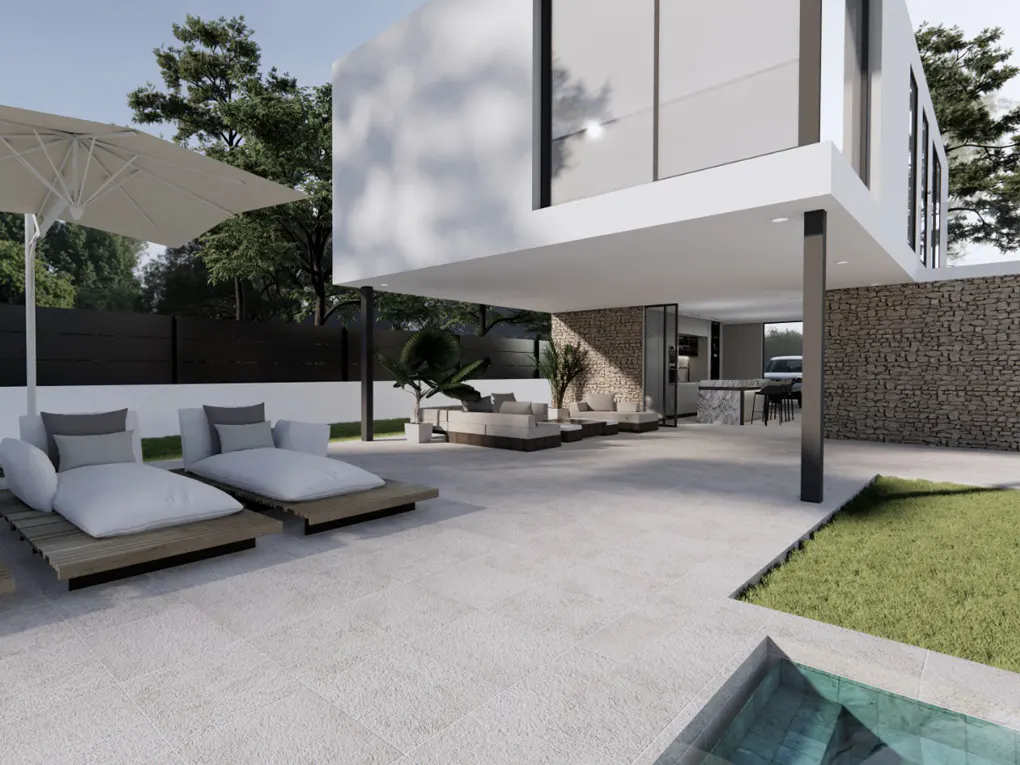 Modern home exterior with lounge chairs, umbrella, and outdoor seating area. Stone wall and green lawn add texture.