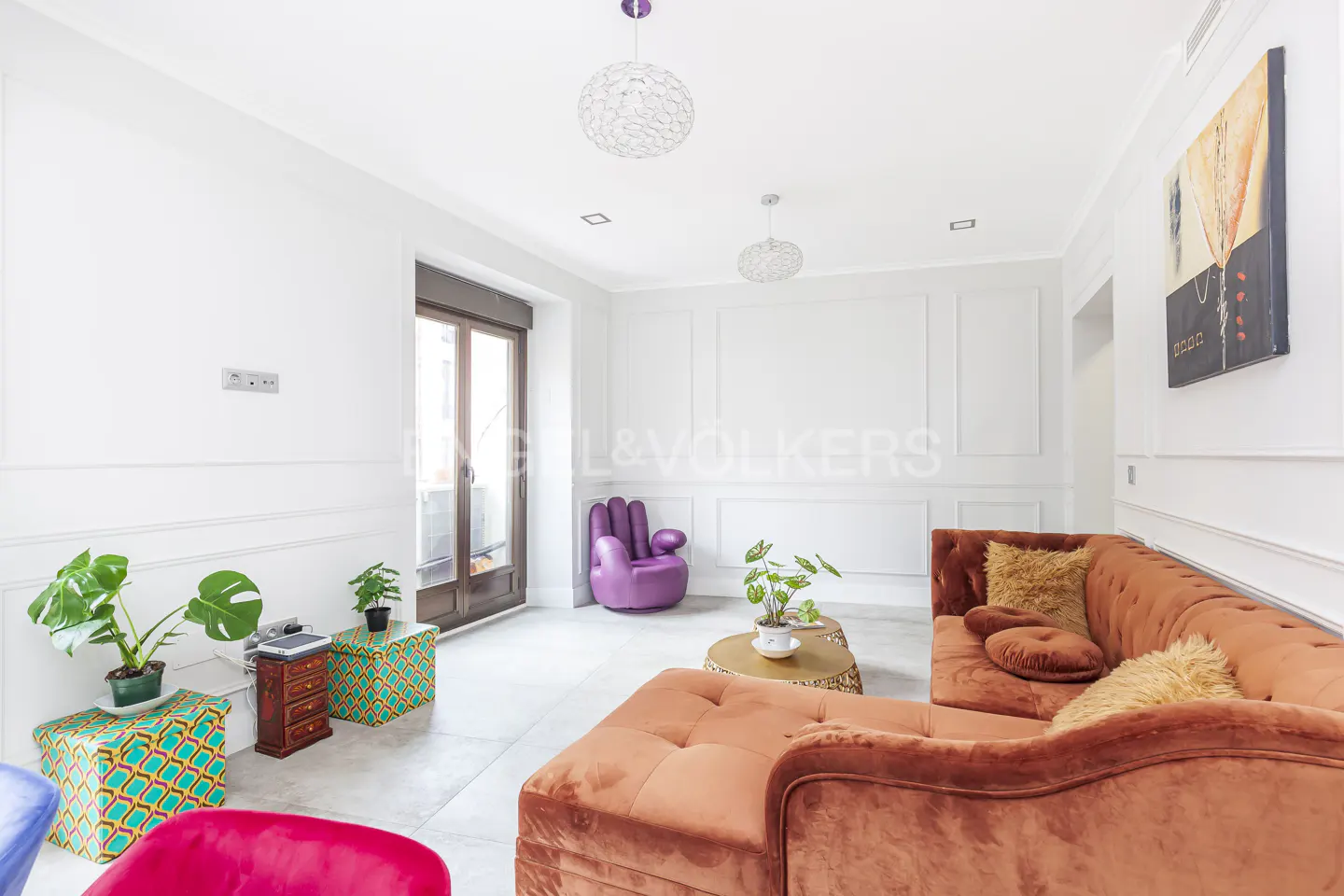 Bright living room with white walls, brown velvet sofa, purple hand chair, and colorful patterned ottomans.
