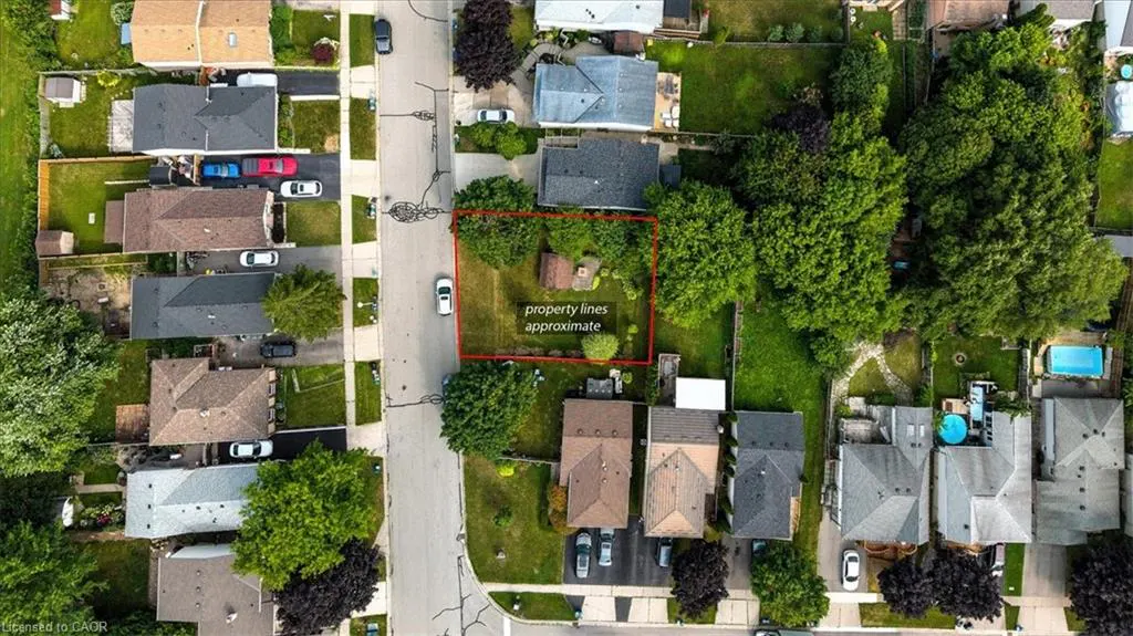 Aerial view of a residential area with houses, trees, and a street. The property lines are marked in red. Text reads "property lines approximate".