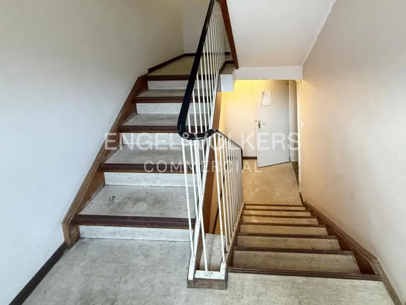 Stairwell with concrete steps, wood trim, and white railing. A white door is visible in the background.