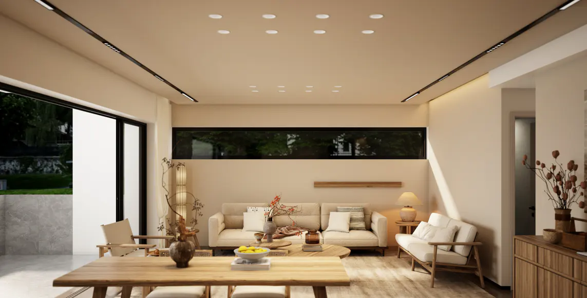 A bright living room with a wooden table, beige sofas, and a large window overlooking a green garden.