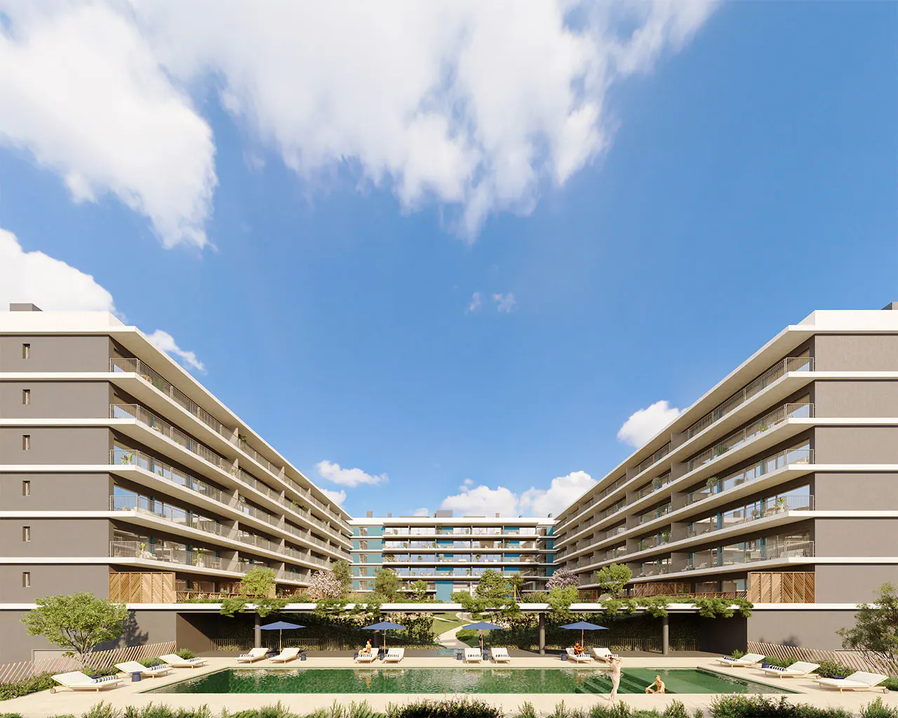 Exterior view of a modern apartment complex with a pool and lounge chairs under a blue sky.