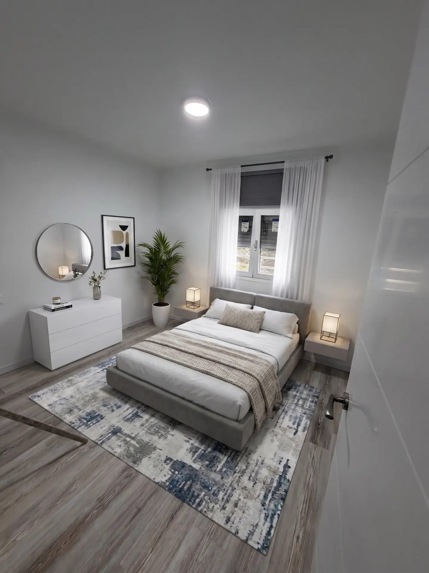 Bright bedroom with a gray platform bed, white linens, and a beige throw blanket. A blue and gray rug sits on the gray wood floor. A white dresser and oval mirror are on the left.