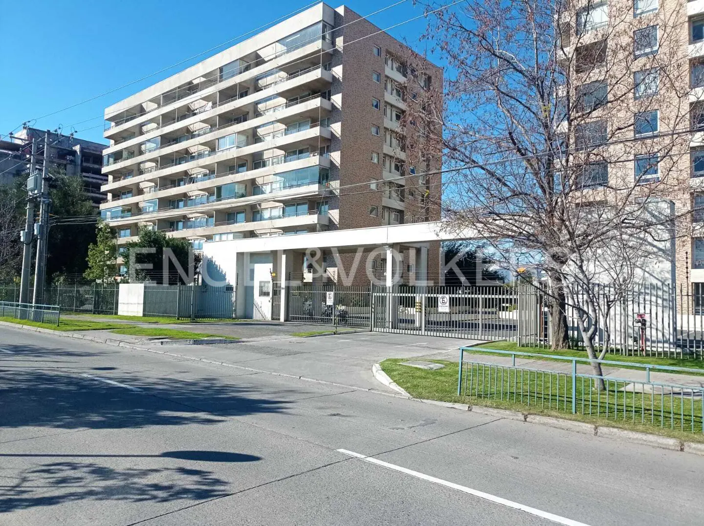 Exterior view of a tall apartment building with balconies, gated entrance, and Engel & Volkers signage.