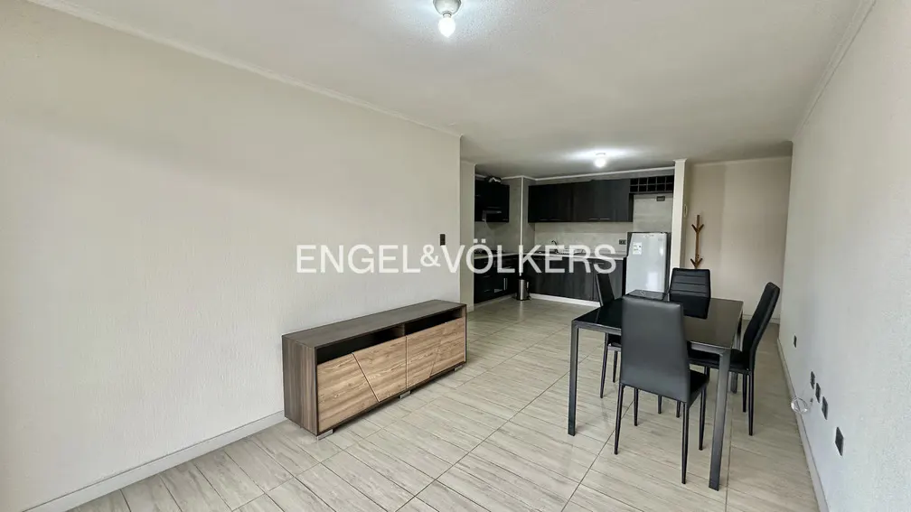 Open-concept apartment with a dining table, gray cabinets, and a wood-look console table. Engel & Völkers logo is visible.