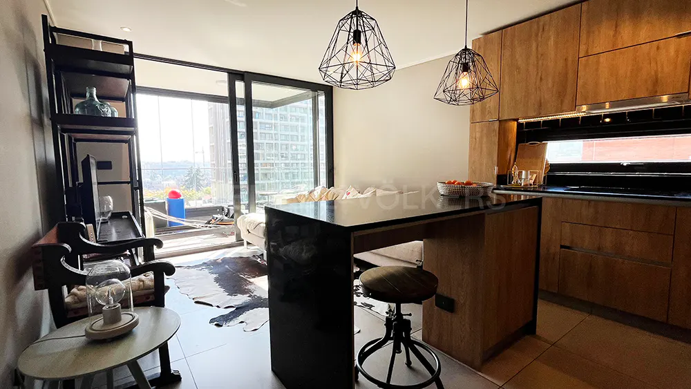 A modern apartment interior with a kitchen island, wooden cabinets, and a living area with a balcony.