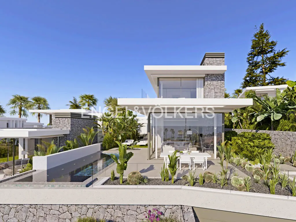 Modern villa with a pool, stone accents, and floor-to-ceiling windows under a clear blue sky. Palm trees and lush greenery surround the property.