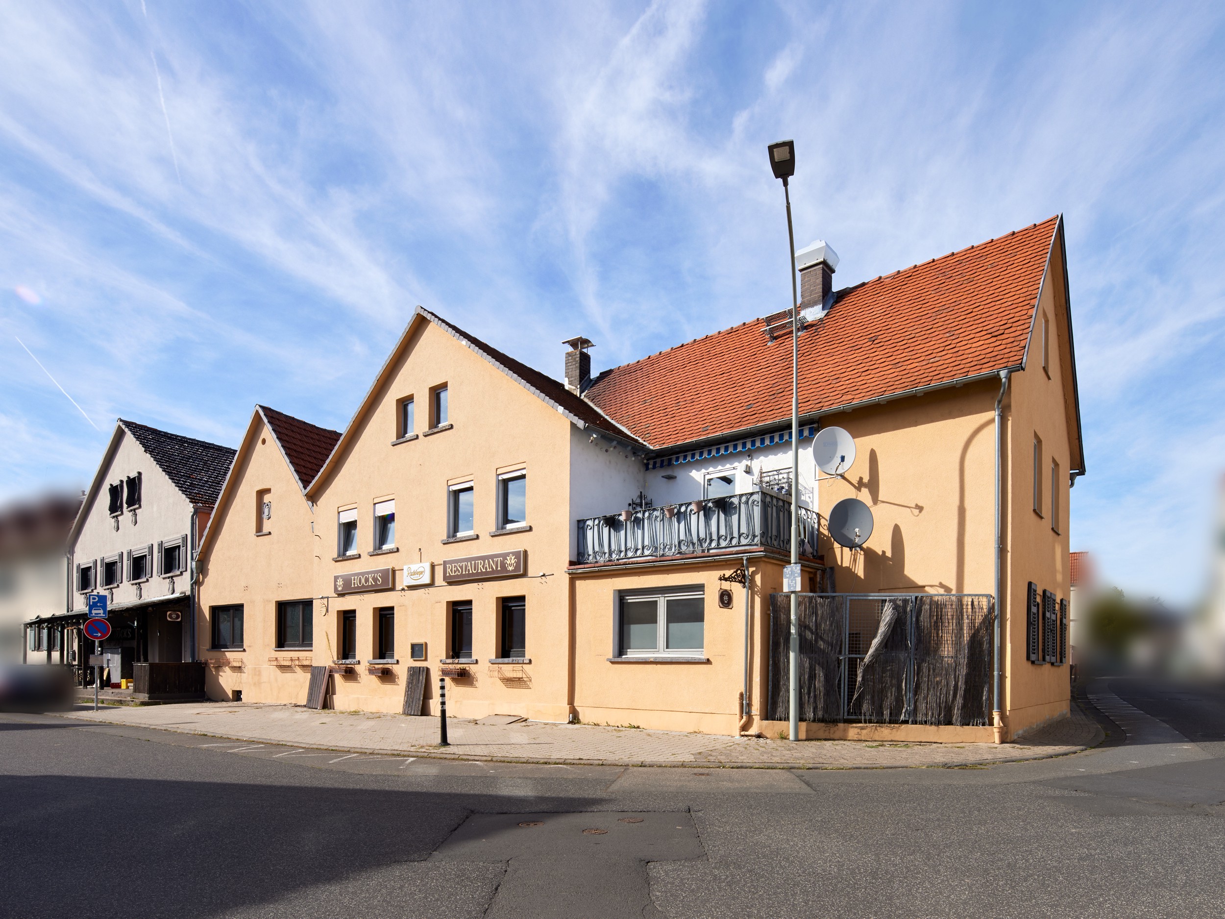 A yellow two-story restaurant building with a red tile roof and a balcony on a sunny day under a blue sky.