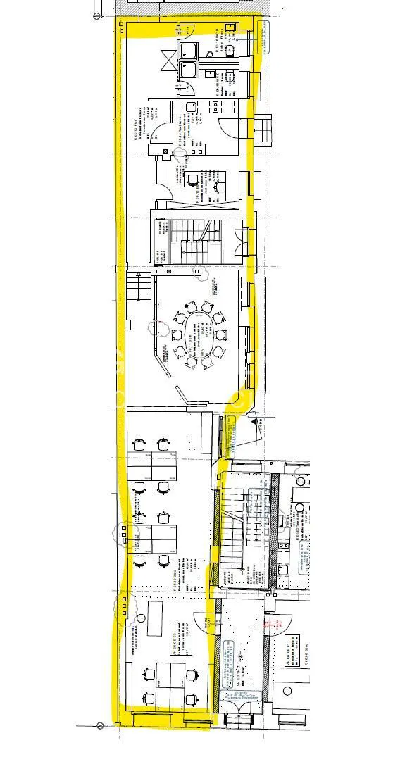 Floor plan of an office space with a yellow border, showing desks, a conference room, stairs, and restrooms.