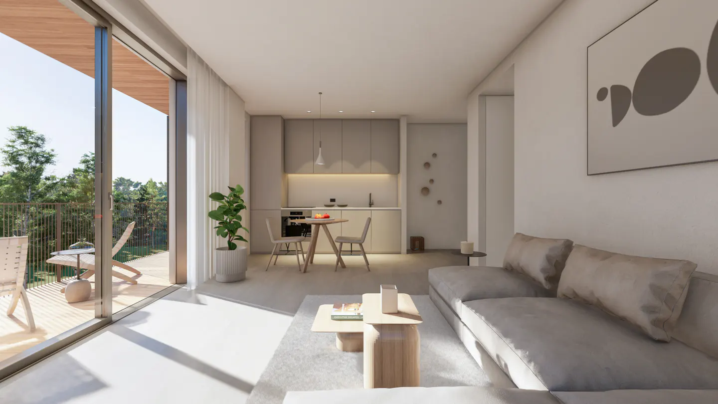 Bright, modern apartment interior with a gray sofa, light wood coffee table, and open kitchen. Balcony with chairs overlooks green trees.