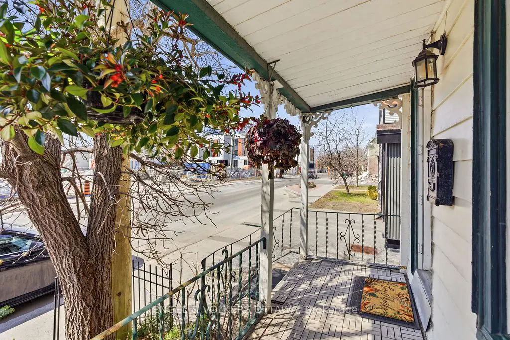 A porch with a hanging plant, a black mailbox, and a view of the street.