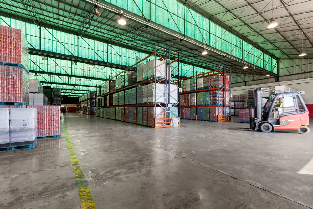 A large warehouse interior with shelves stacked with goods and a forklift.