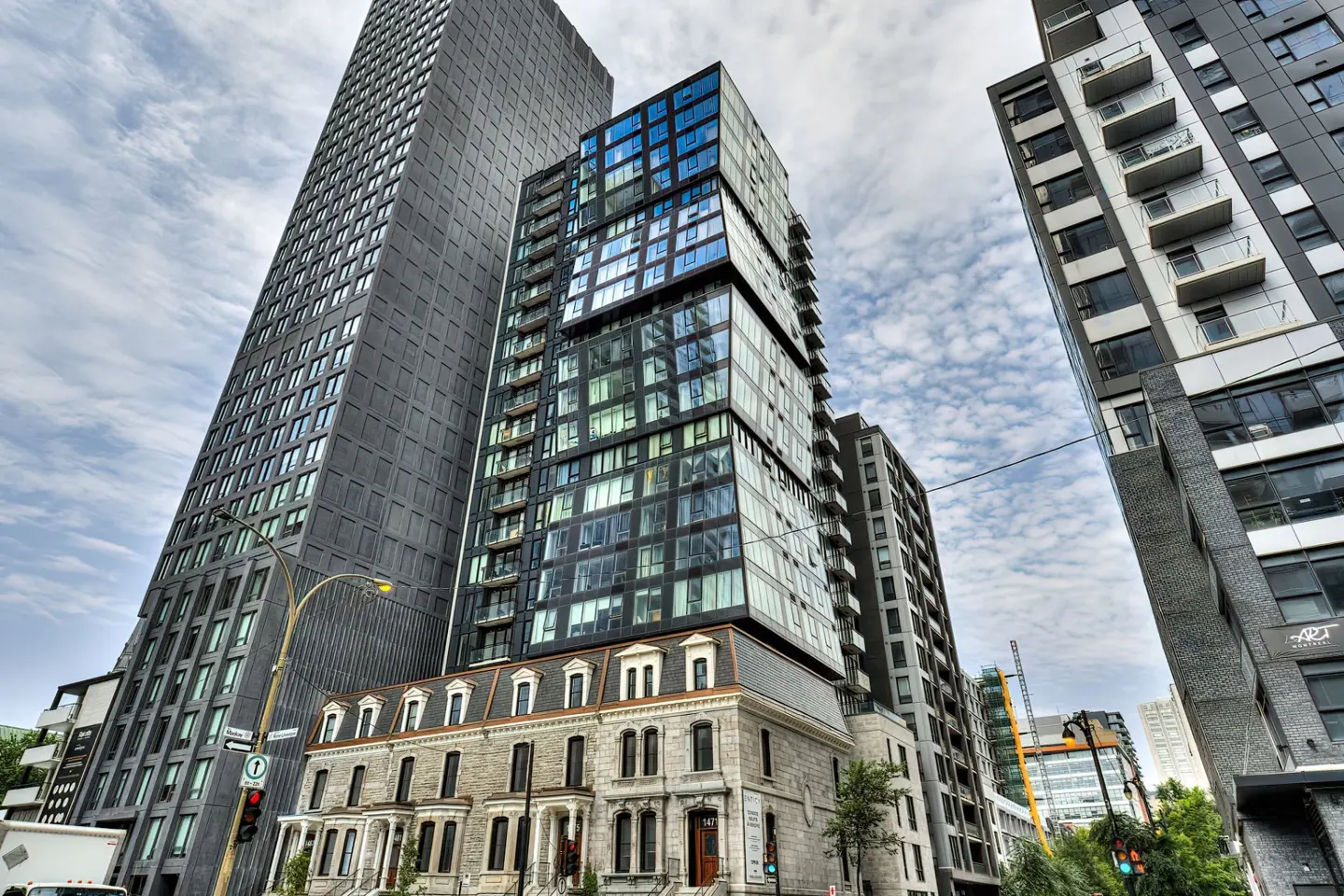 Cityscape view of modern high-rise buildings next to older stone buildings under a cloudy sky.