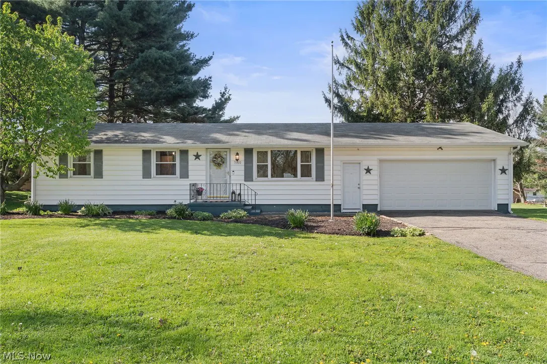 A white ranch-style house with gray shutters, a front lawn, and a two-car garage.
