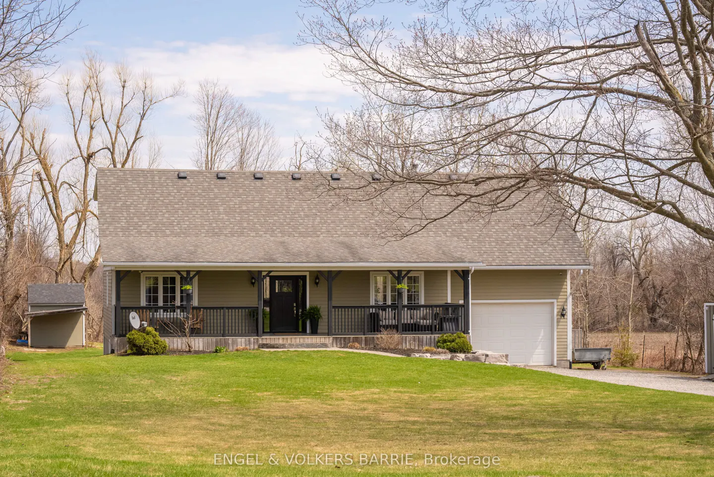 A single-story house with a gray roof, a black door, and a white garage door. A green lawn is in front of the house.
