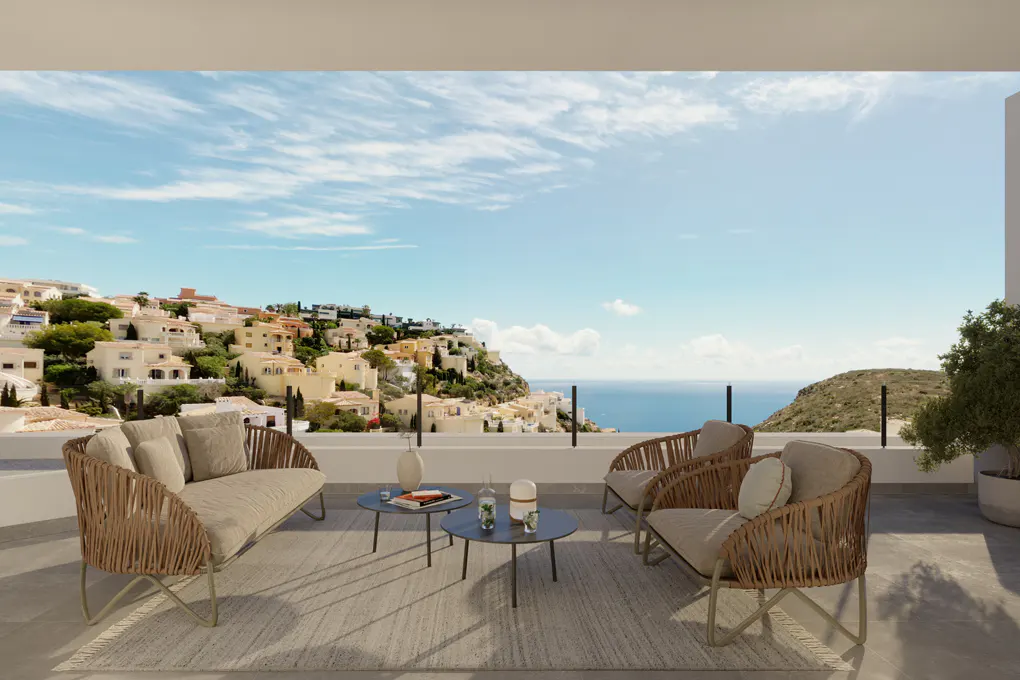 Outdoor patio with wicker furniture overlooking a coastal town and ocean on a sunny day.
