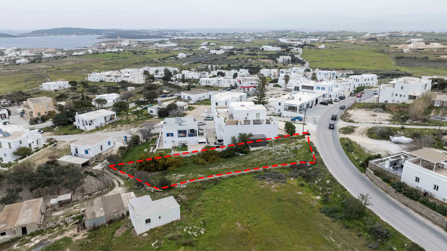 Aerial view of a vacant lot outlined in red, surrounded by white buildings and a road in Paros, Greece.