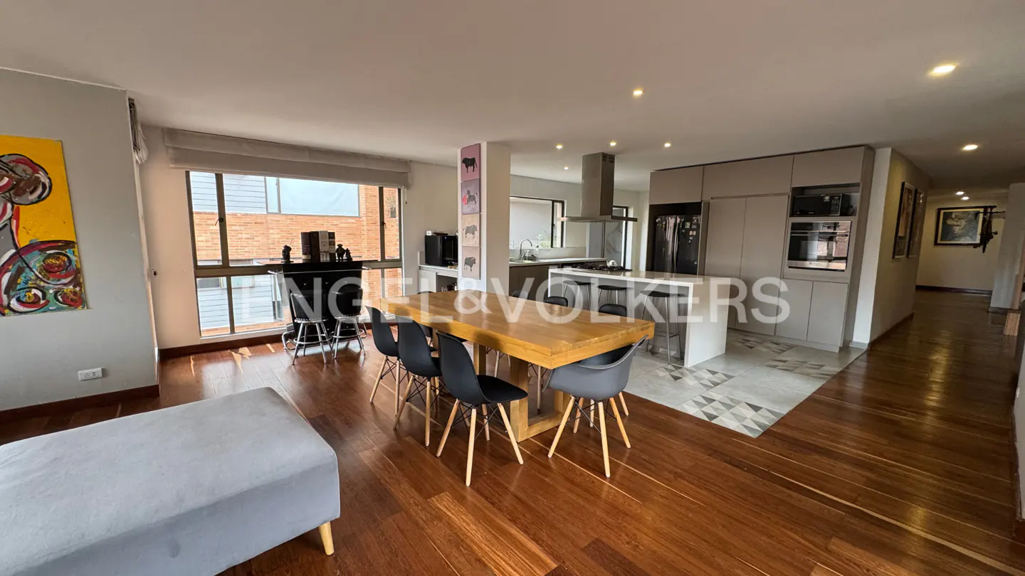 Open-concept living space with wood floors, a dining table, and a modern kitchen with stainless steel appliances.