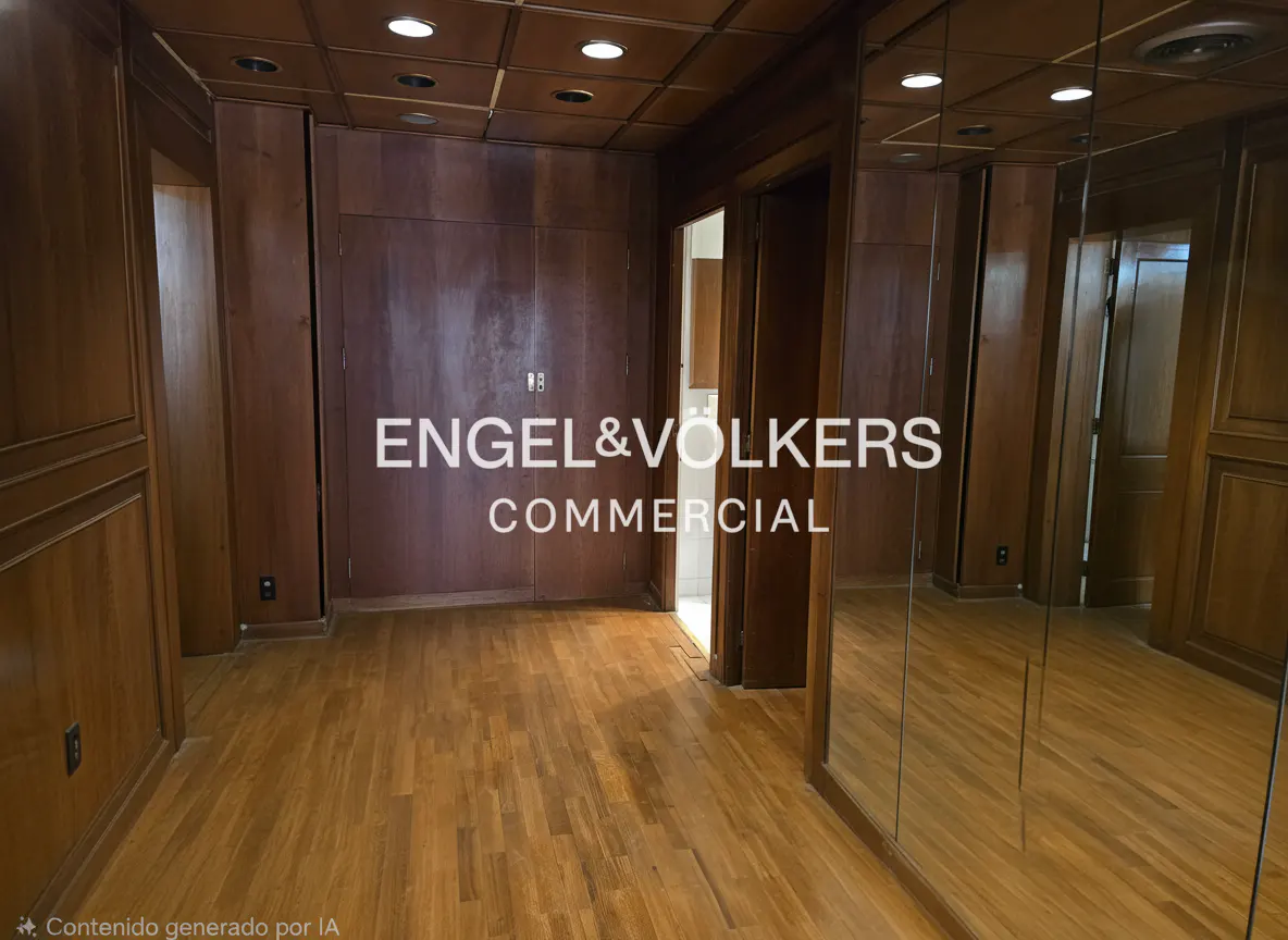 A room with wood paneling, wood floors, and mirrored walls. A doorway leads to another room. The Engel & Volkers Commercial logo is superimposed.