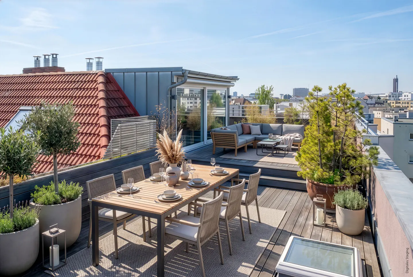 Rooftop patio with a wood dining table set for eight, a gray sectional sofa, and potted plants, with a city view in the background.