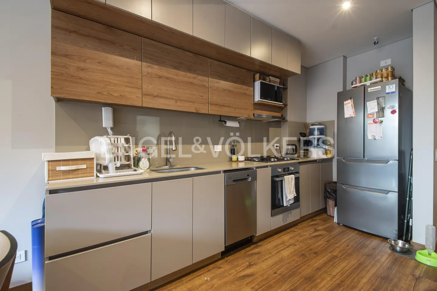 Modern kitchen with wood floors, gray cabinets, stainless steel appliances, and wood upper cabinets.