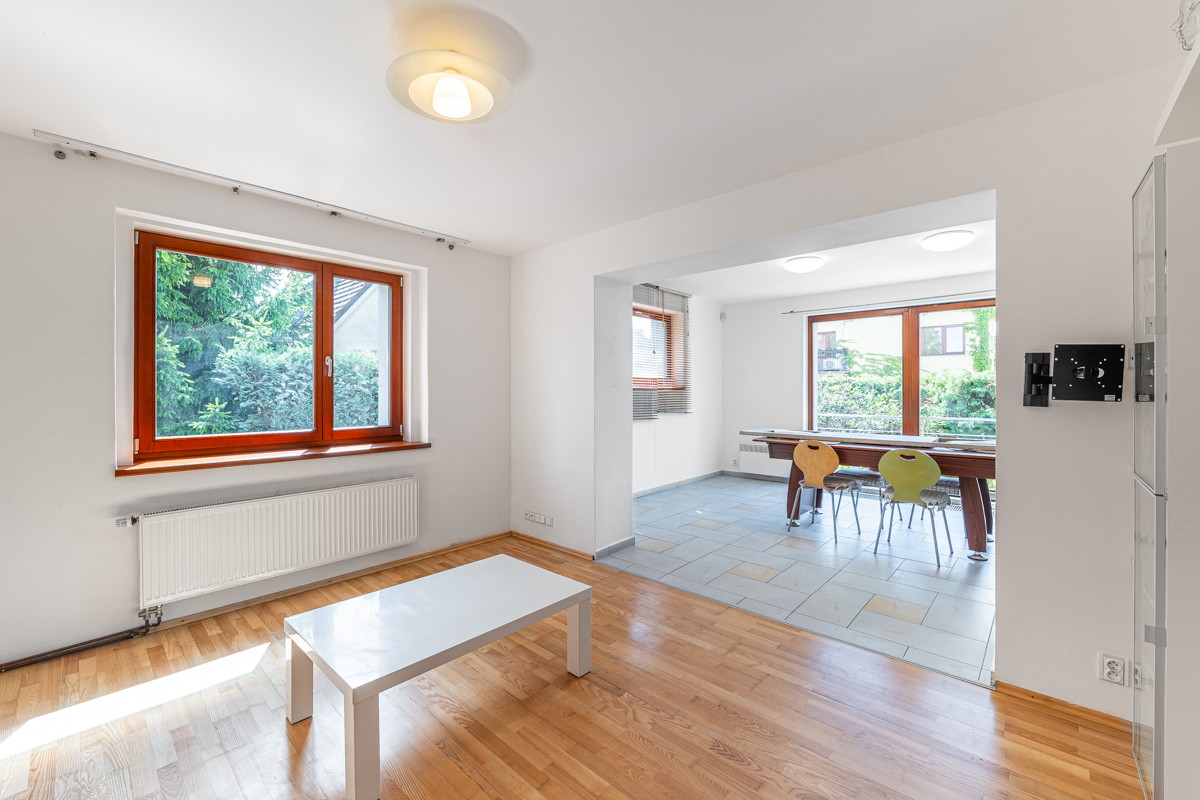 Bright living room with hardwood floors, a white coffee table, and an open dining area with a table and colorful chairs. [AI-generated text]