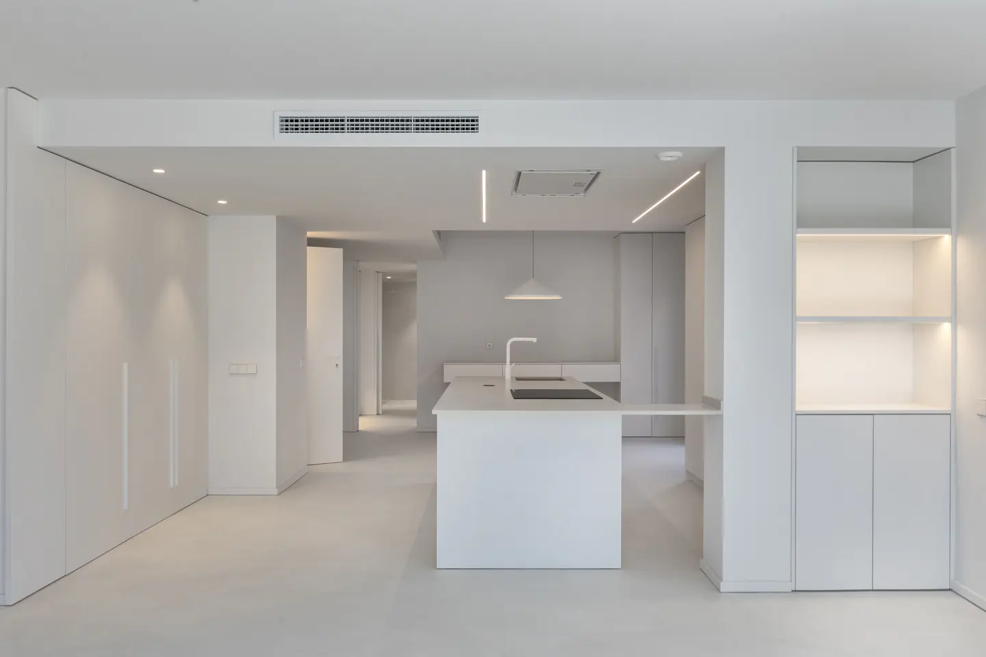A bright, all-white modern kitchen with an island, sink, and open shelving.