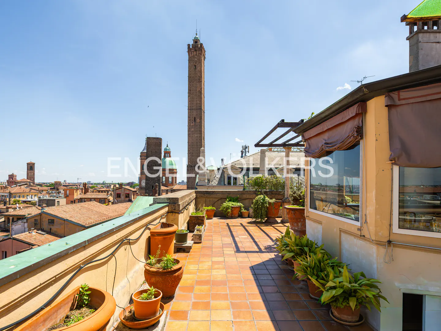Rooftop terrace with terracotta tiles and potted plants overlooking Bologna, Italy. Two Towers visible in the background.
