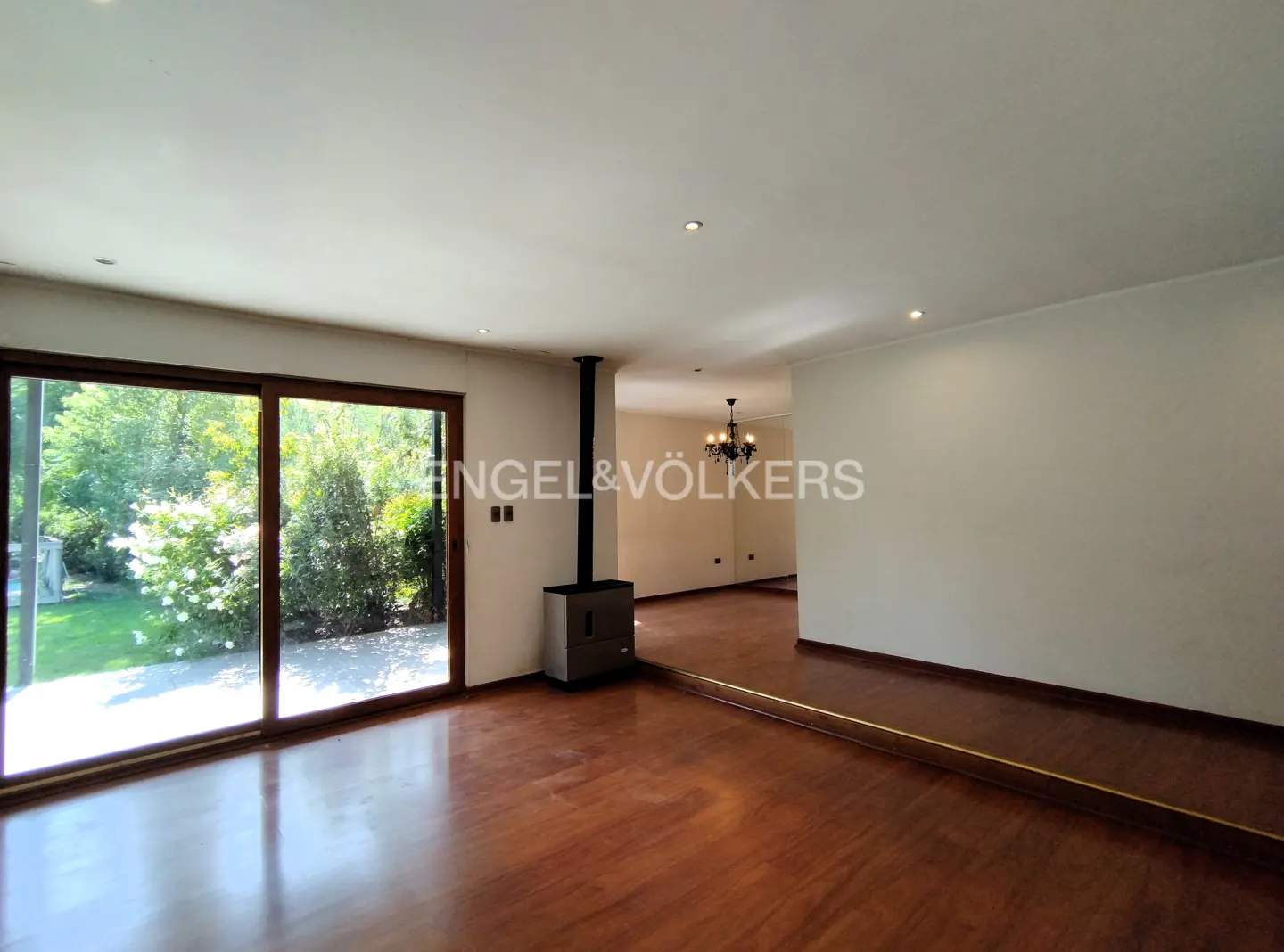 A bright living room with wood floors, a fireplace, and a large sliding glass door to a green yard.
