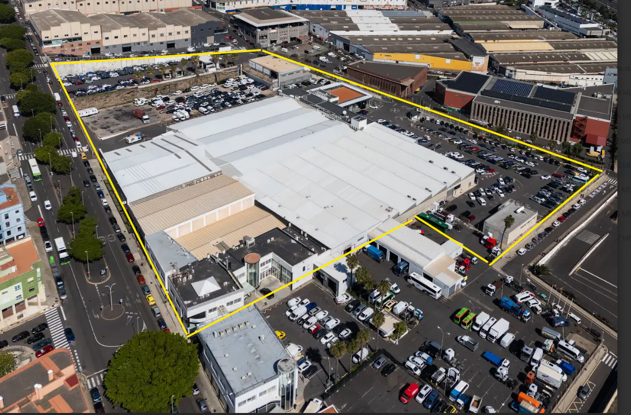 Aerial view of a large, white industrial building surrounded by parking lots and outlined in yellow.