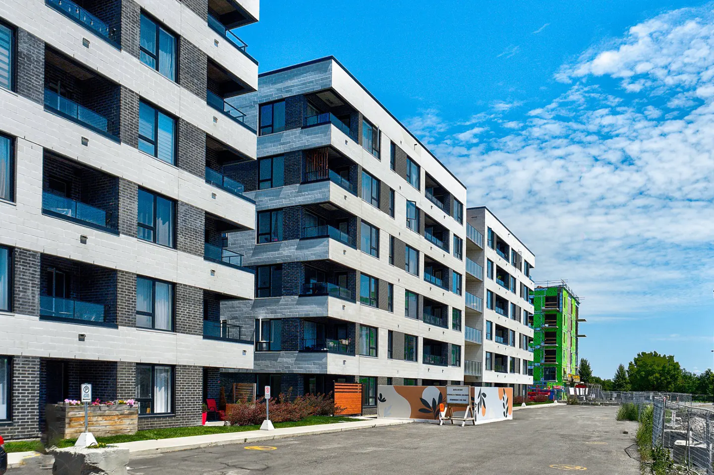 Modern apartment buildings with balconies under a blue, cloudy sky.